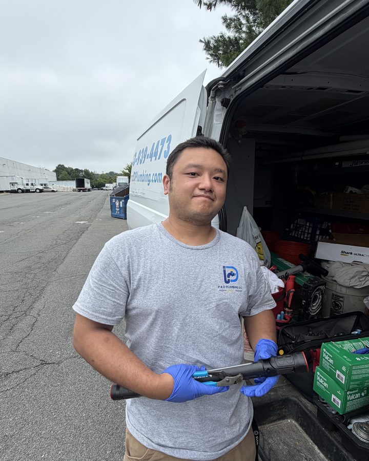 P & D Plumbing technician with a press tool beside the company van